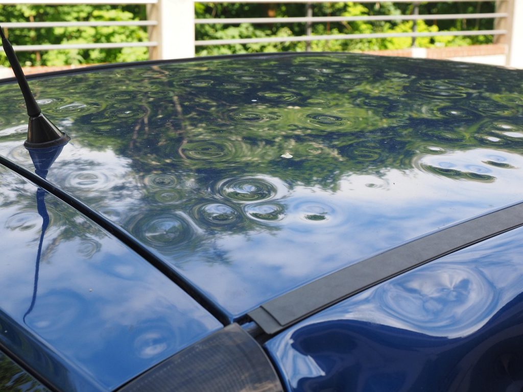 close-up of hail dents on the roof of a blue car