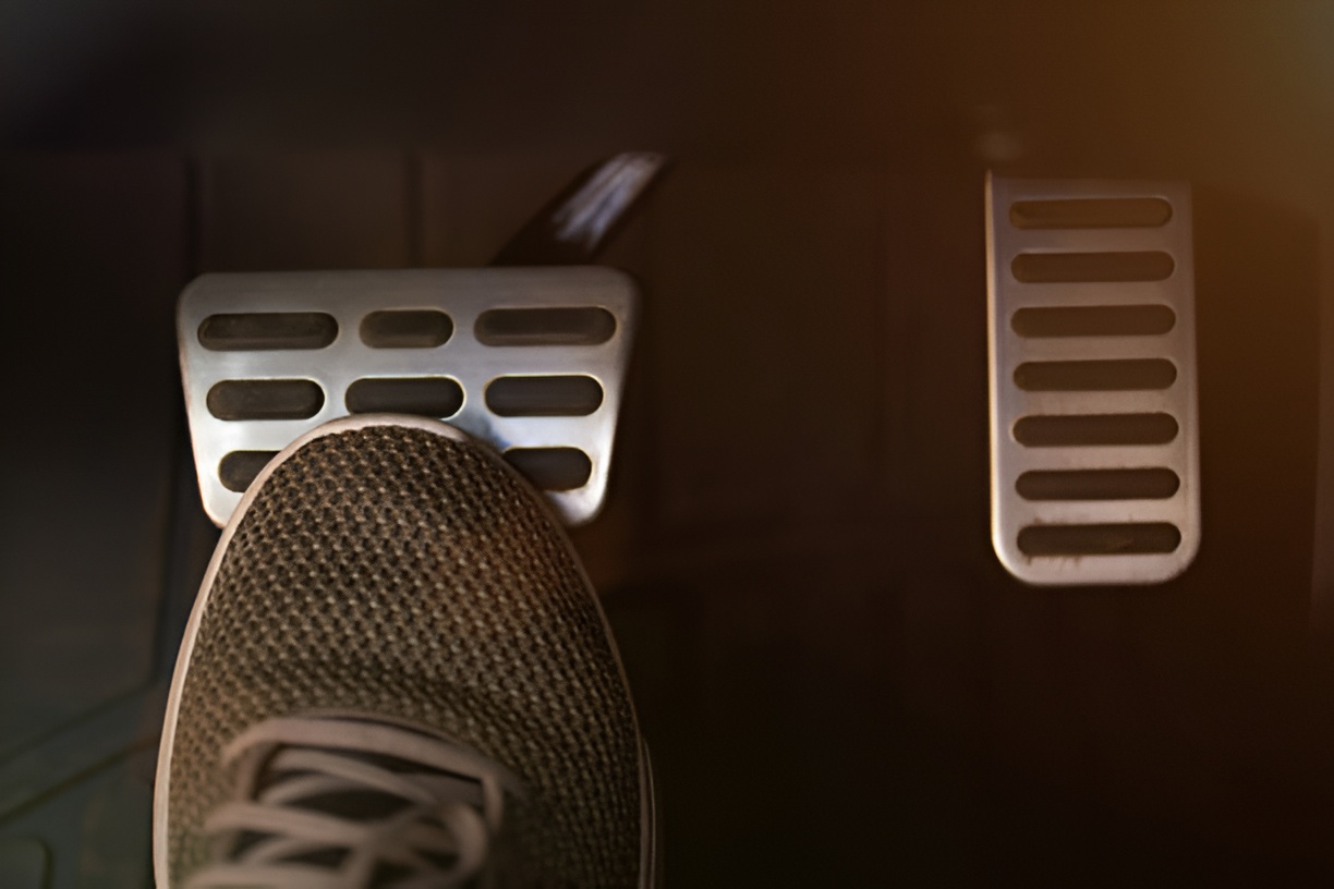 close-up of a foot in a brown sneaker pressing a brake pedal