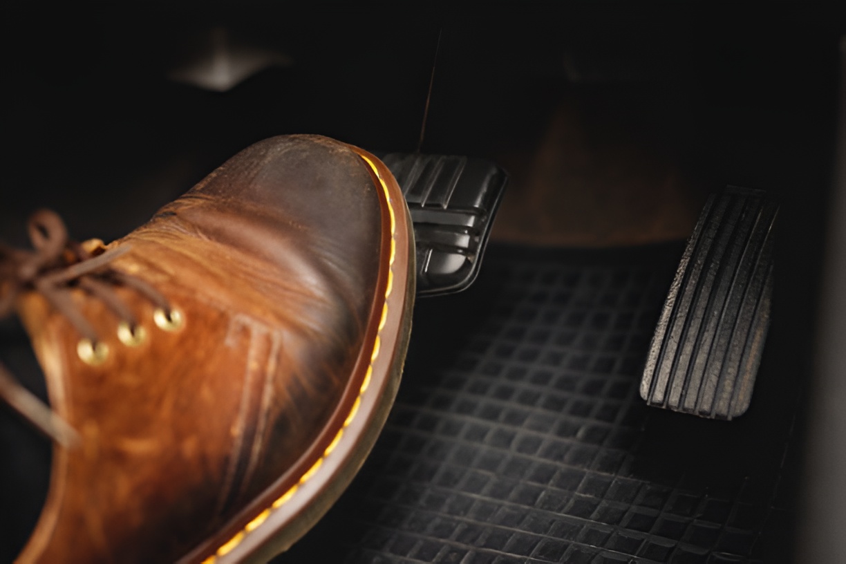 close-up of a foot in a brown leather shoe pressing a brake pedal
